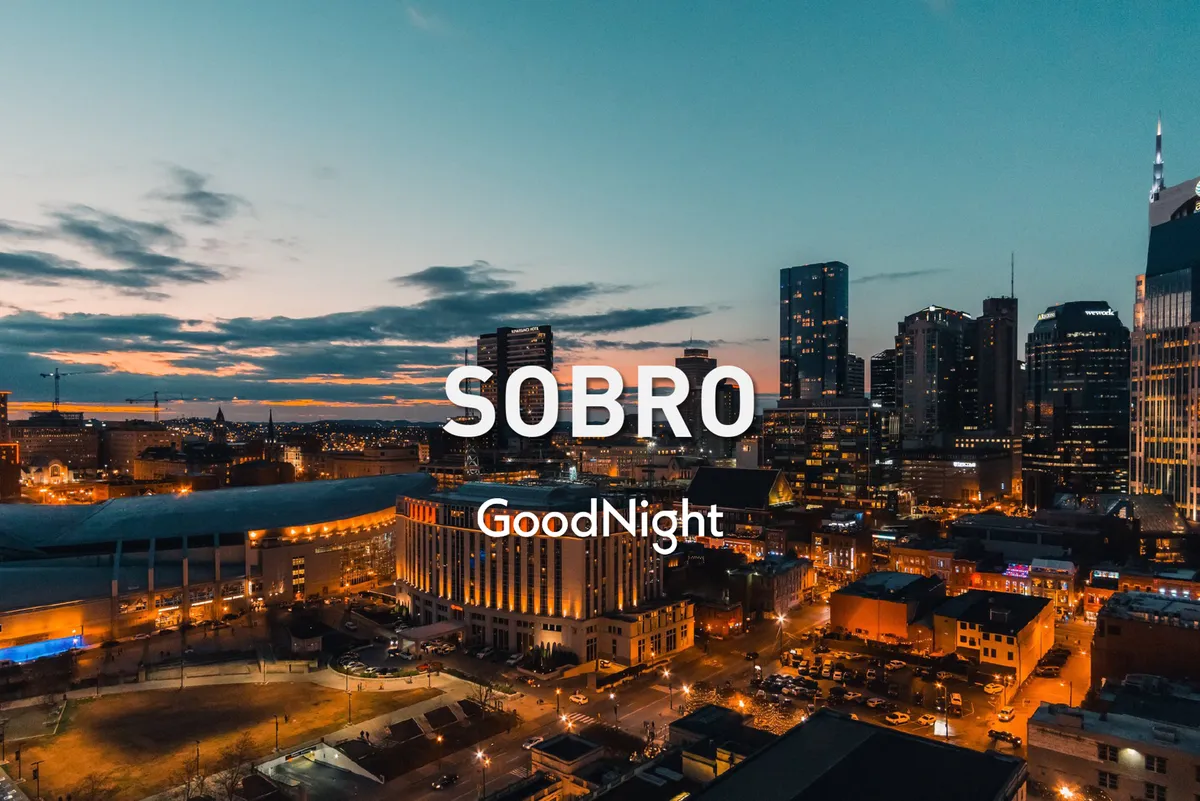 A panoramic view of the Nashville city skyline at sunset, with building lights glowing and the sky painted in warm hues. The scene feels relaxed yet connected to the urban core, suggesting both accessibility and the opportunity to unwind after work.