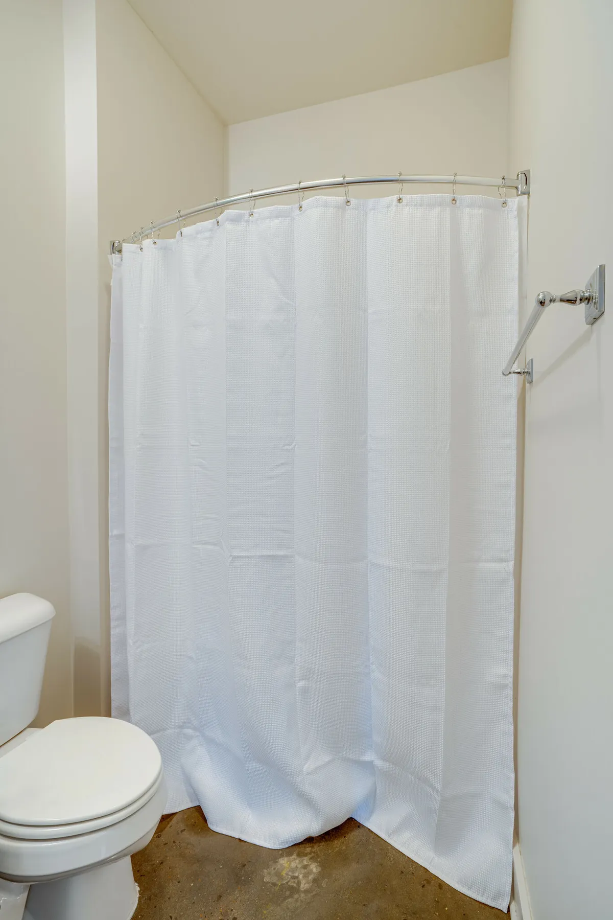 A functional bathroom featuring a shower curtain and toilet, set in a clean, neutral space. The scene emphasizes practicality and everyday comfort, reinforcing the essentials aspect of the section.