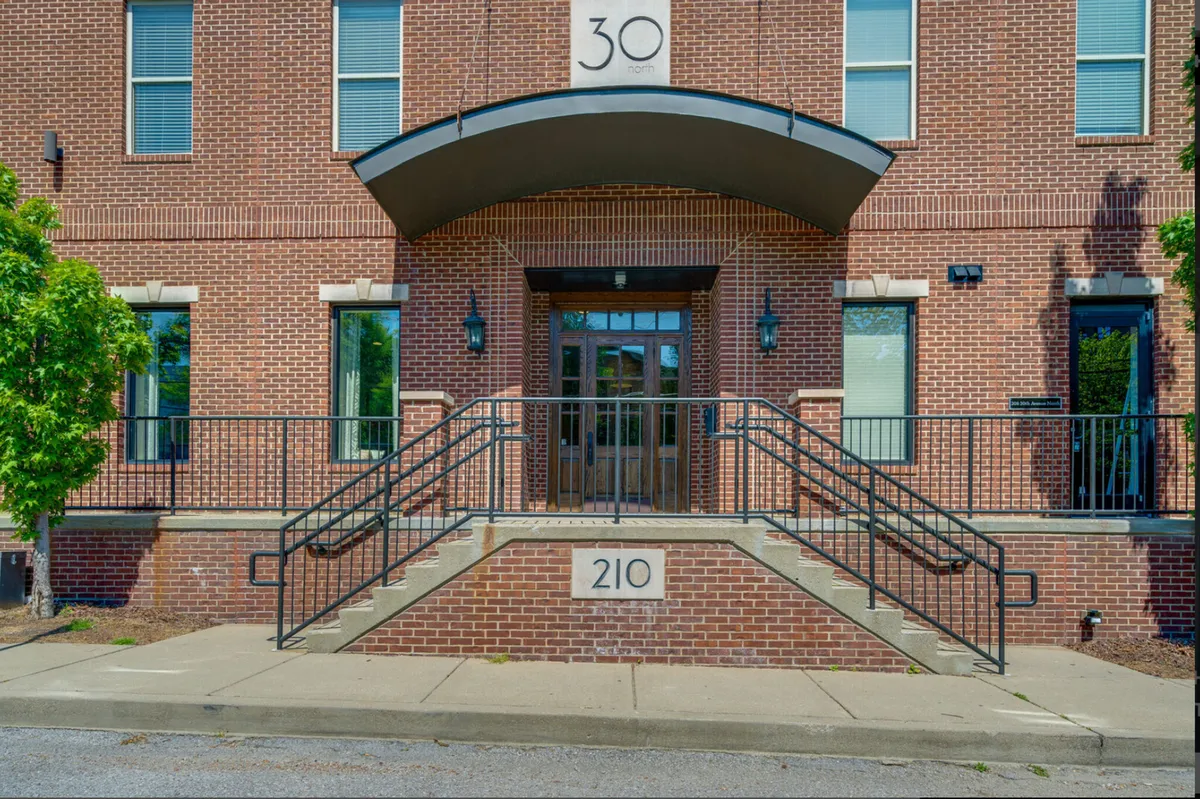 The exterior entrance of the building, showcasing the brick facade, address, and welcoming stairs under an arched canopy. The professional and inviting appearance highlights secure, managed access and a well-maintained property.